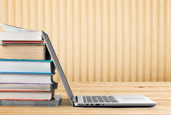 Стопка книг с ноутбуком на столе
