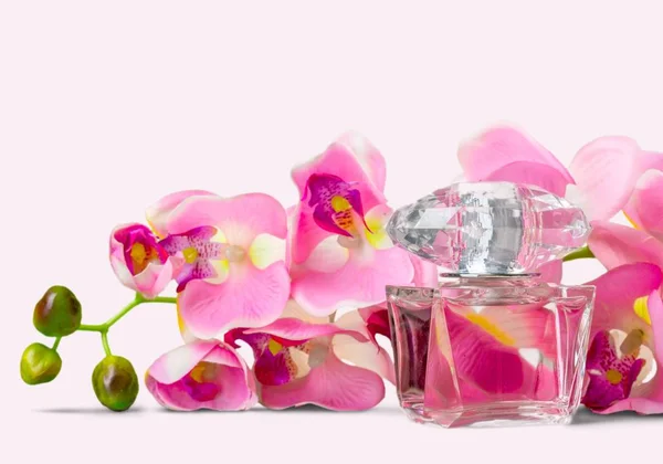 香水瓶和模糊的背景上的花朵 — 图库照片