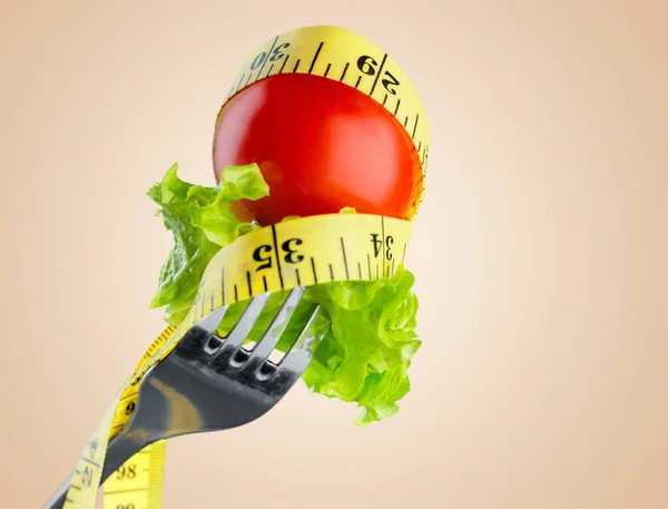 在叉子上的新鲜生蔬菜和在背景上隔离的测量胶带 — 图库照片
