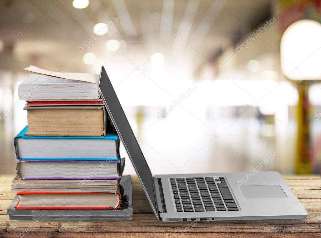 Stack of books and laptop, modern education background