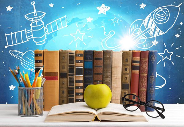 row of books, pencils, eyeglasses, green apple on open book