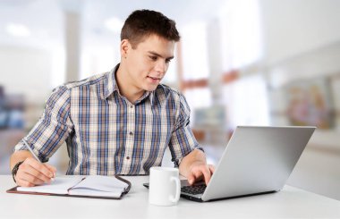 Bilgisayarda çalışan mutlu genç adam.