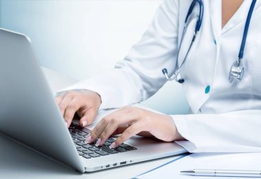 Doktor dizüstü bilgisayarda yazıyor.