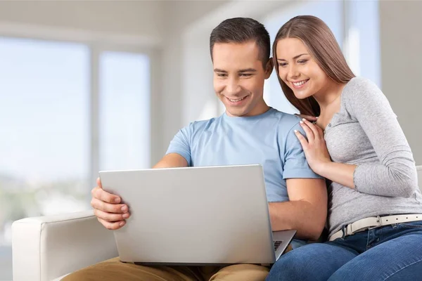 Smiling couple with laptop on sofa — Stock Photo, Image