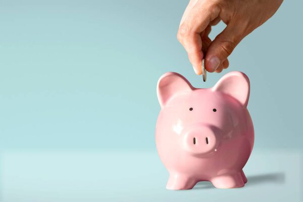 Businessman putting coin into the piggy bank