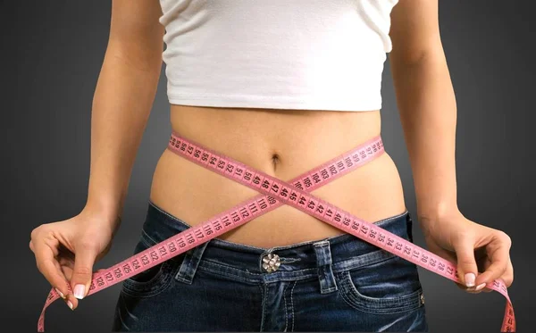 Mujer joven midiendo su delgada cintura — Foto de Stock