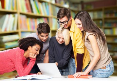 Dizüstü bilgisayar ve kitap okuyan genç öğrenciler  