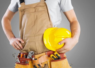 Genç adam işçi alet kemeri ve kask ile