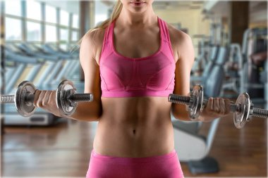 young fit woman training with dumbbels in gym