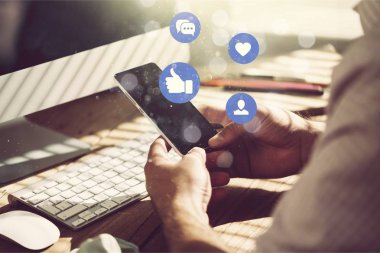 Arka planda telefon ve bilgisayar olan eller 
