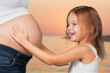 hamile kadının karnına dokunan küçük kız 