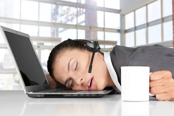 tired woman in headset sleeping on laptop
