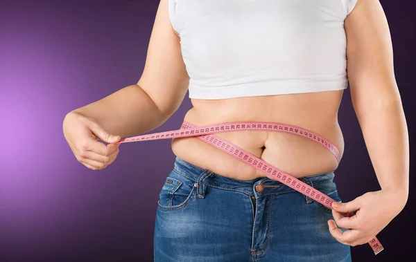 有胖肚子的女人测量她的腰部的背景 — 图库照片
