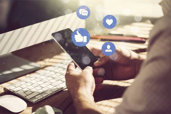 Arka planda telefon ve bilgisayar olan eller 