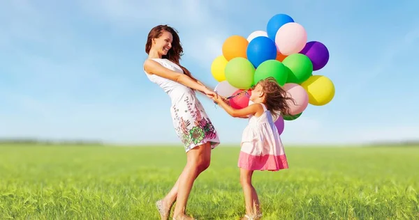 Mãe com filha segurando balões coloridos — Fotografia de Stock