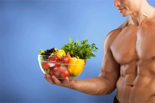 muscular man holding plate with vegetables, food for bodybuilder