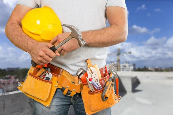 Young man worker with tool belt and helmet