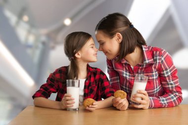 Genç anne ve kız evde süt içiyor. 