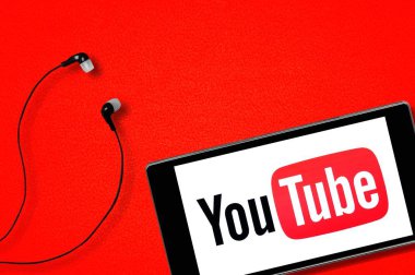 Youtube uygulaması akıllı telefonda çalışıyor. Kulaklıklar kırmızı arkaplanda. 