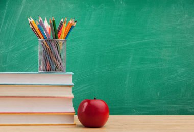 kitap yığını, kırmızı elma ve renkli kalemler