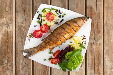 Beyaz tabakta sebzeli ızgara balık.