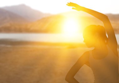 Gün batımında sahilde yürüyen bir kadın.