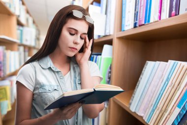 Kütüphanede kitabı olan genç bir kadın.