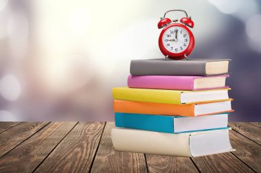 Bir yığın kitap ve klasik çalar saat.