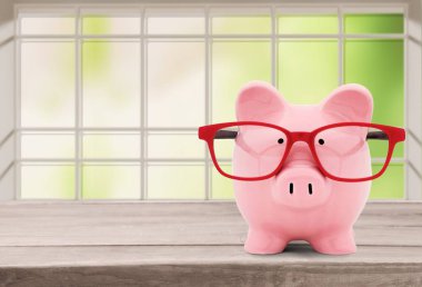 ahşap masa üzerinde gözlük pembe kumbara