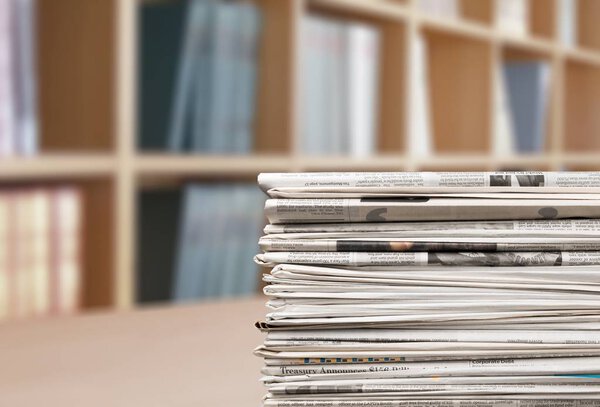 stack of newspapers on a wooden table.