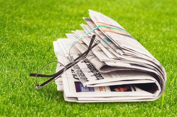 Stapel Zeitungen Und Brillen Auf Grünem Gras — Stockfoto