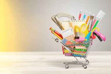 school supplies and tools in shopping cart on wooden background