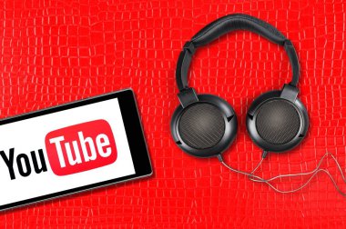 Youtube uygulaması akıllı telefonda çalışıyor. Kulaklıklar kırmızı arkaplanda. 