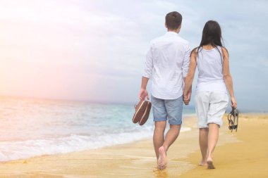 Genç bir çift sahilde yürüyor. 