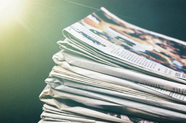 Tahta bir masanın üzerinde gazete yığını.