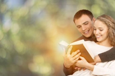 Genç çift parkta kitap okuyor.