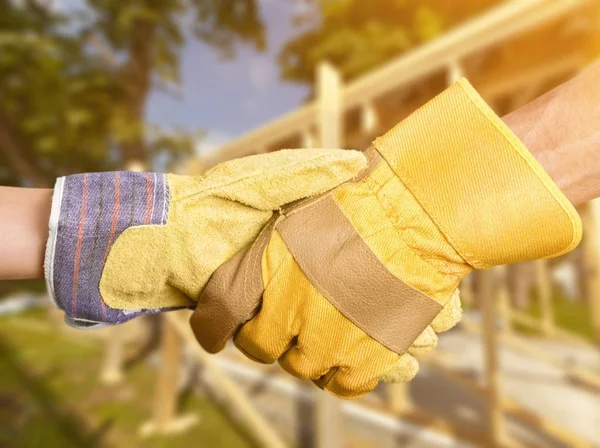 two hands in work gloves handshaking