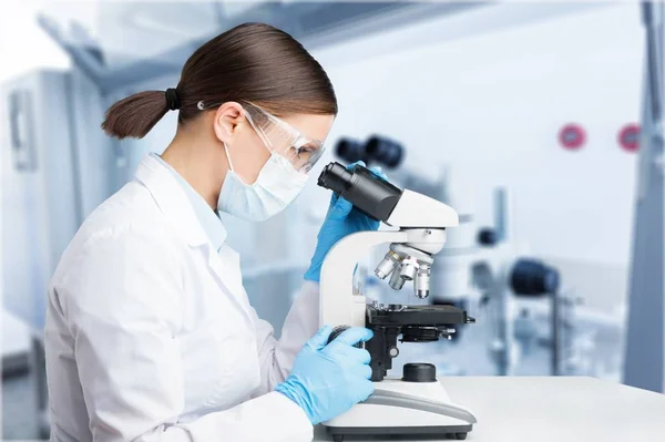 研究室で顕微鏡を使う若い女性 — ストック写真