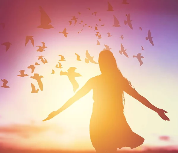 Woman at sunset, birds in the sky