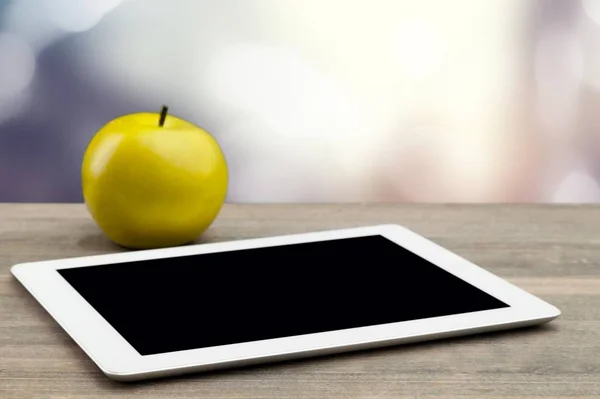 digital tablet and green ripe apple