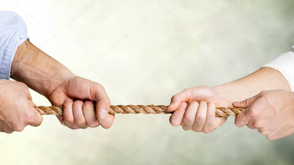 business people pulling rope in opposite directions at office