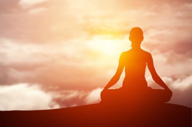 Gün batımında meditasyon yapan kadın silueti