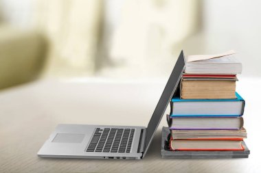 Masada dizüstü bilgisayar ve kitap yığını