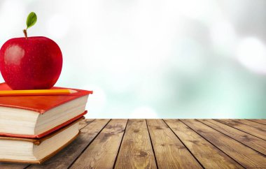 kitap yığını ve masada taze elma