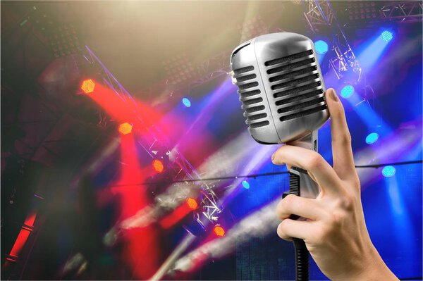 Retro style microphone and hand on abstract background