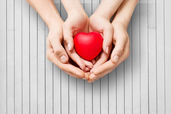 Man and woman holding red heart on background 