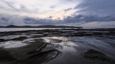 Şafakta sudaki yansımalar Avustralya 'nın NSW merkez sahilindeki Umina Sahili' nde.