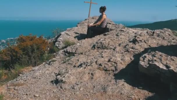 Mujer viajera se sienta en la cima de una montaña rocosa — Vídeo de stock