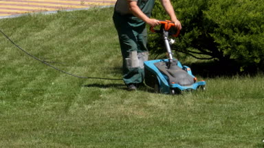 Taşınabilir bir elektrik Lawnmower adamla parkta çim yeşil çimlere Mows