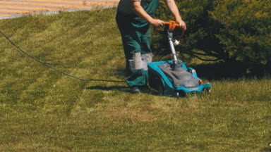 Taşınabilir bir elektrik Lawnmower adamla parkta çim yeşil çimlere Mows